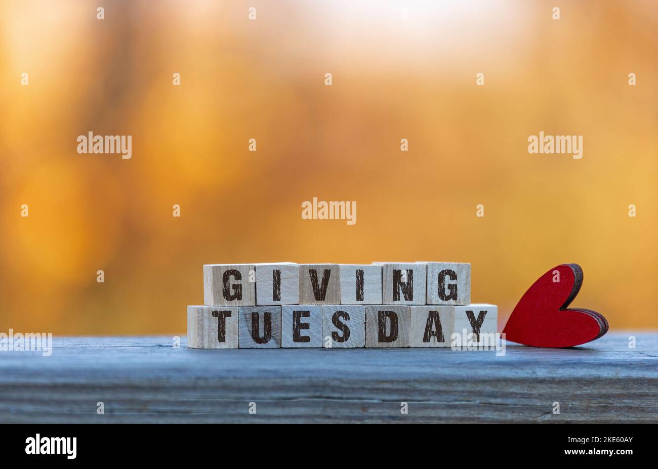 Giving Tuesday text on wood blocks with red heart golden leaves bokeh background Stock Photo