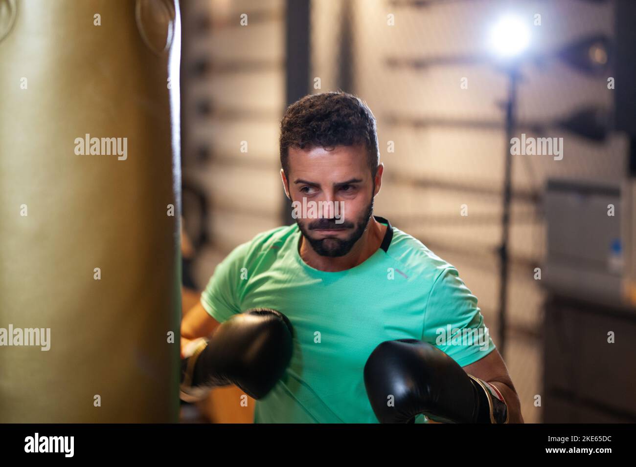 Muscular man with boxing gloves hitting a punching bag in a fitness