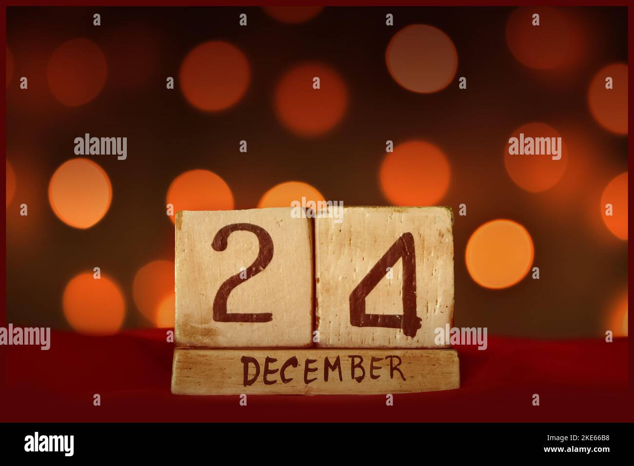 December 24 Christmas Eve vintage wooden block calendar on red fabric, festive bokeh lights background greeting card celebrating holidays, birthday, s Stock Photo