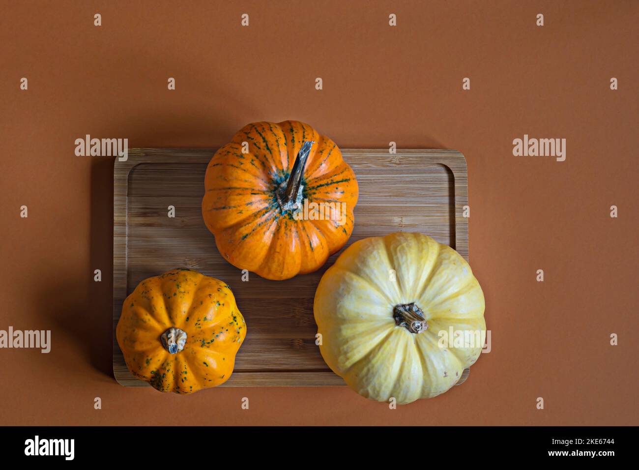 Decorative pumpkins on a wooden tray on an orange (terracotta ...