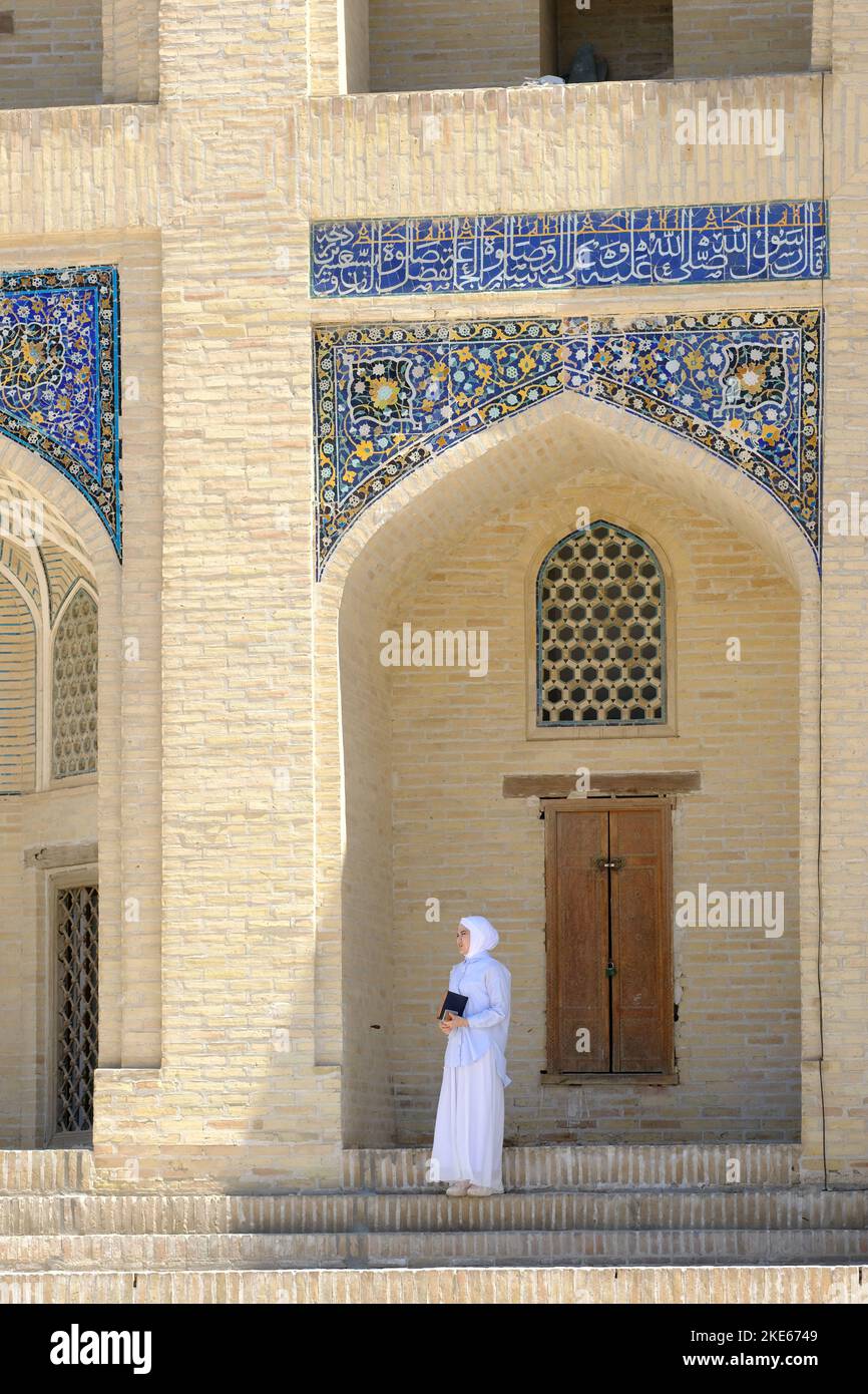 Bukhara Uzbekistan a woman standing in the shade outside the decorated ornate Mir I Arab Madrasa in August 2022 Stock Photo