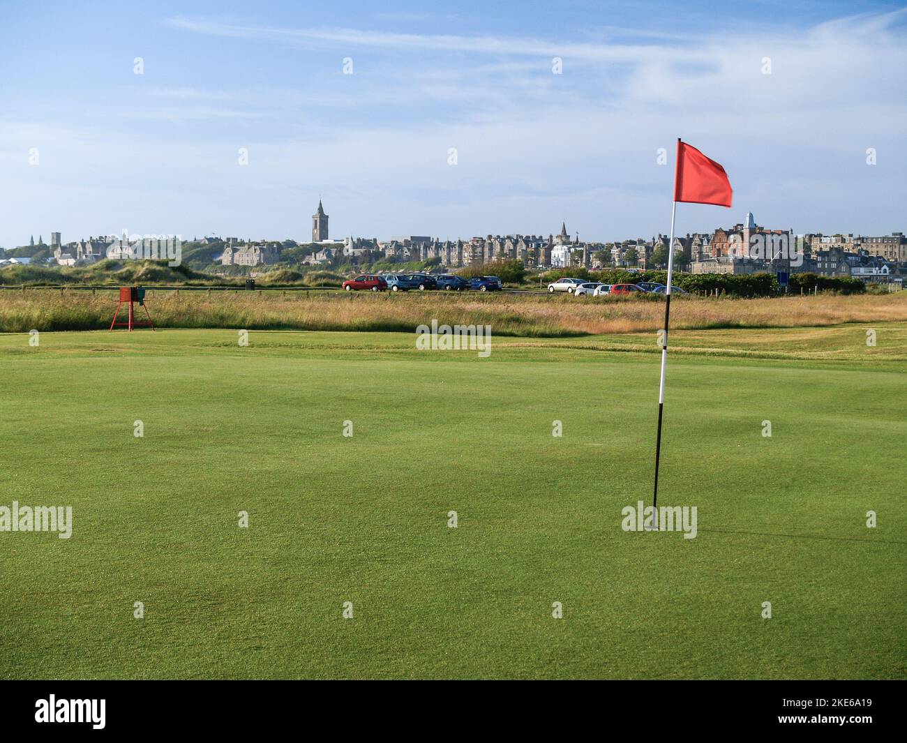 Red hole flag on golf course with urban skyline behind at St Andrews