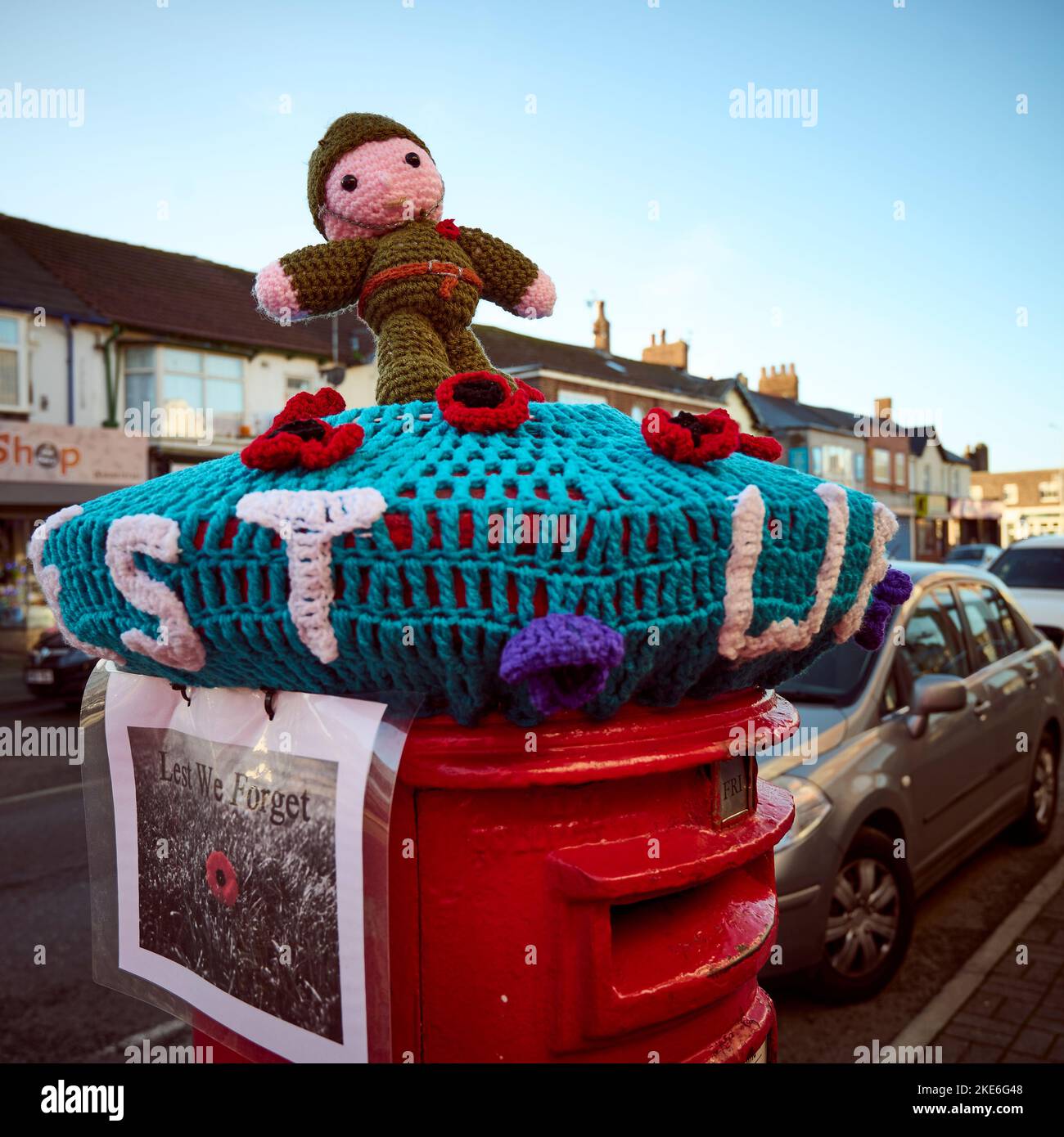Least we forget,knitted remembrance theme on top of post box on street corner Stock Photo
