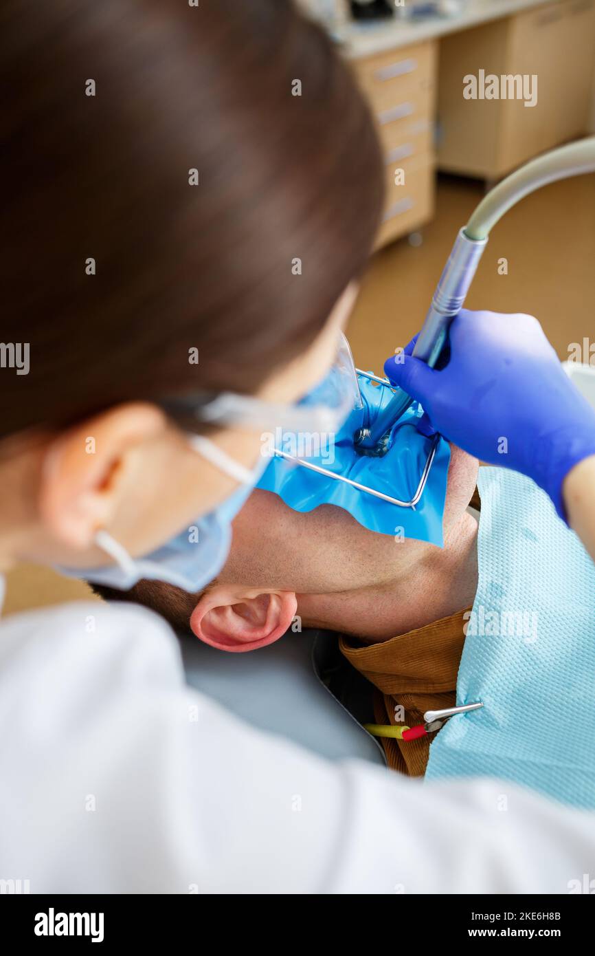 Male patient sits on the dentist's chair and receives teeth restoration