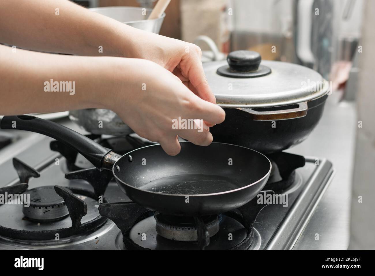 hand of a woman opening an egg to fry it in a small frying pan, preparing a typical Colombian breakfast. Stock Photo