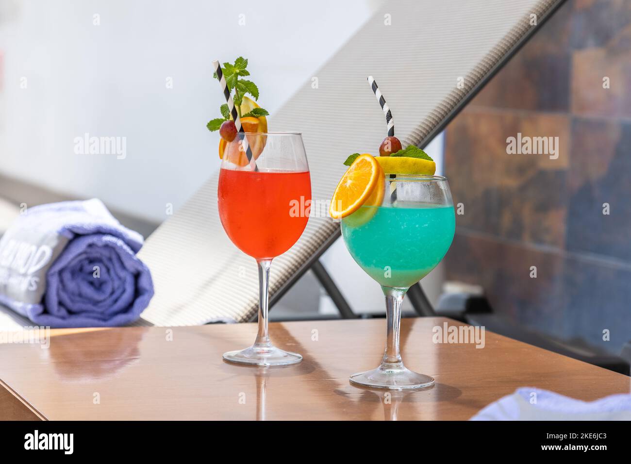 The glasses of Spritz and Blue Hawaii cocktails in hotel room on wooden table Stock Photo