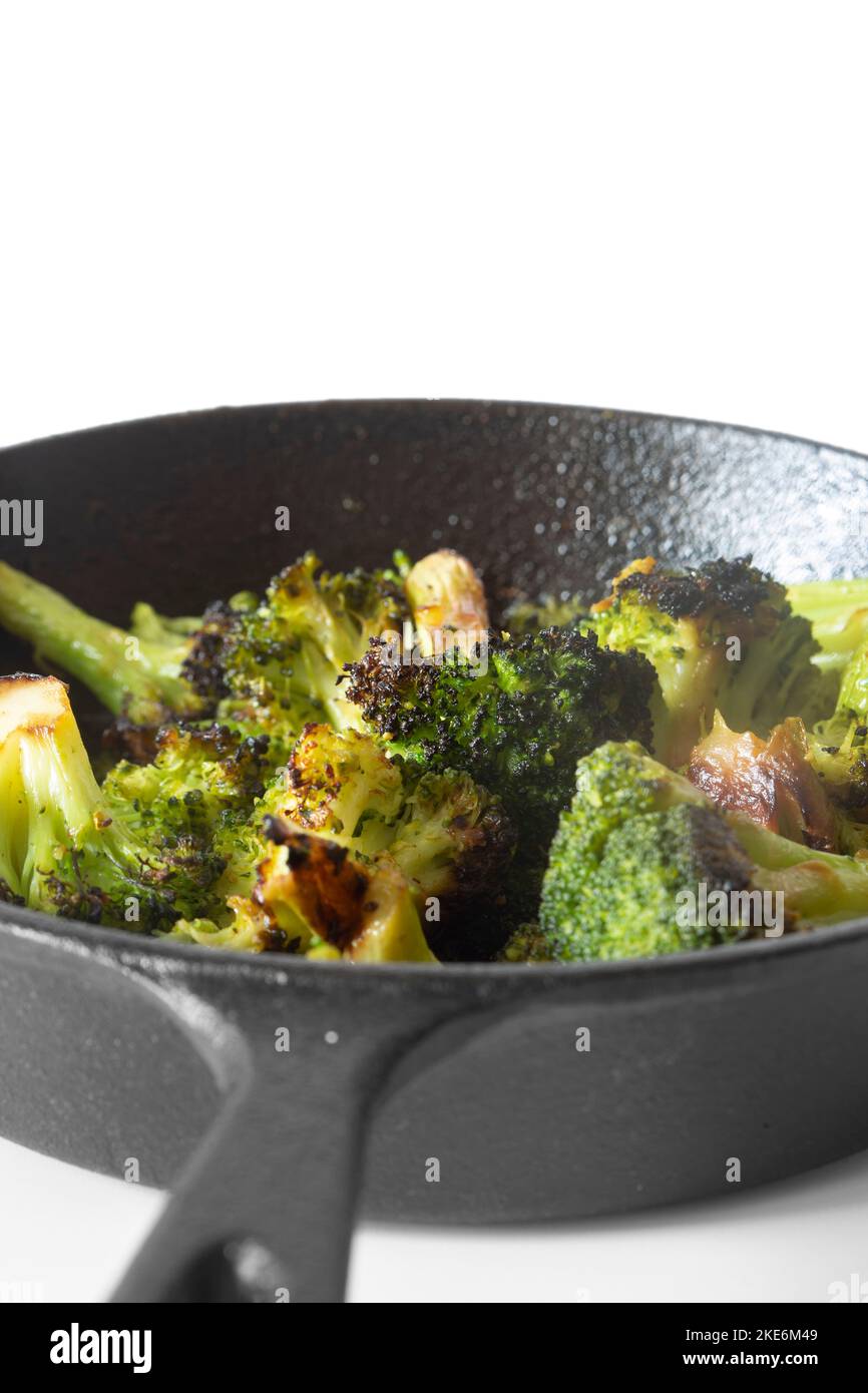 Broccoli fried, in a cast iron frying pan with olive oil. Isolated on a white background Stock Photo