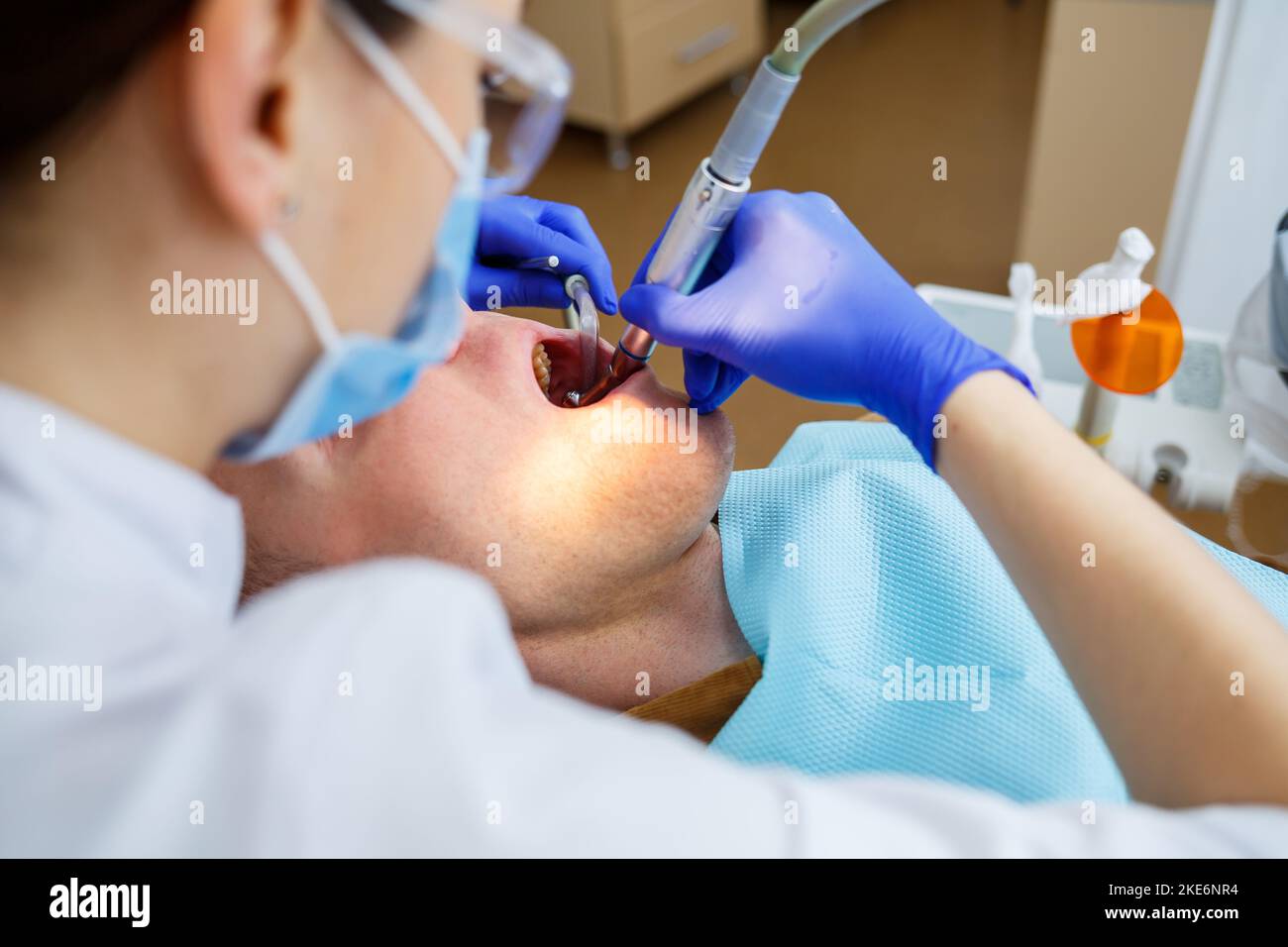 A female dentist treats tooth decay on a male patient's teeth at a dental clinic during the coronavirus pandemic. Selective focus Stock Photo