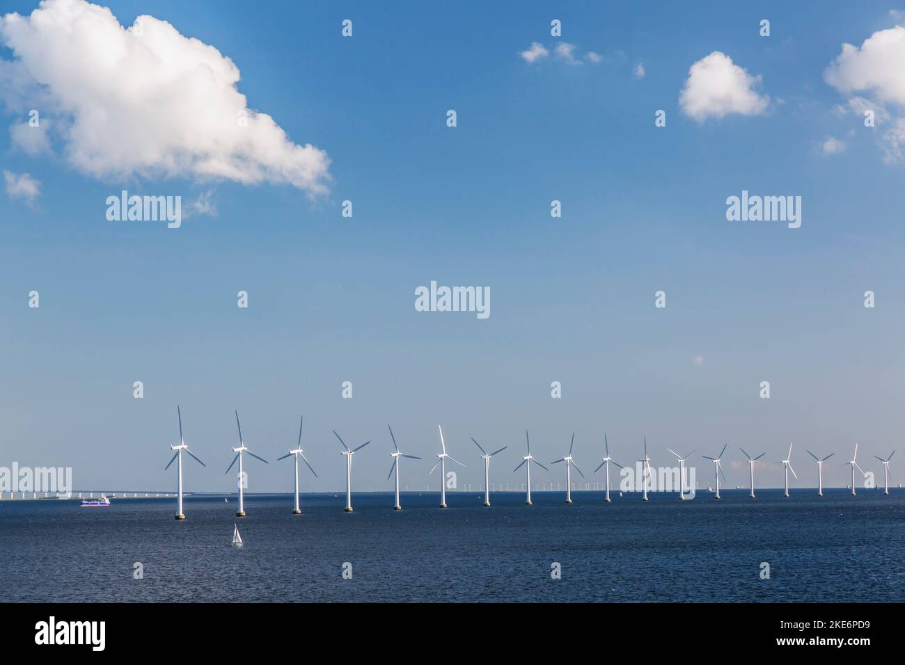 Small sailboat and row of wind turbines in Baltic Sea producing electricity off the coast of Denmark. Stock Photo