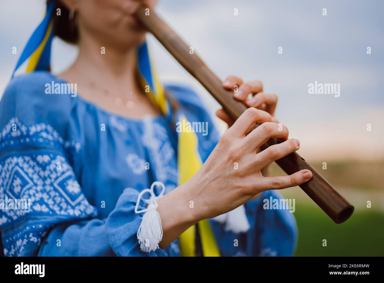 Woman playing woodwind wooden flute ukrainian sopilka outdoors. Folk