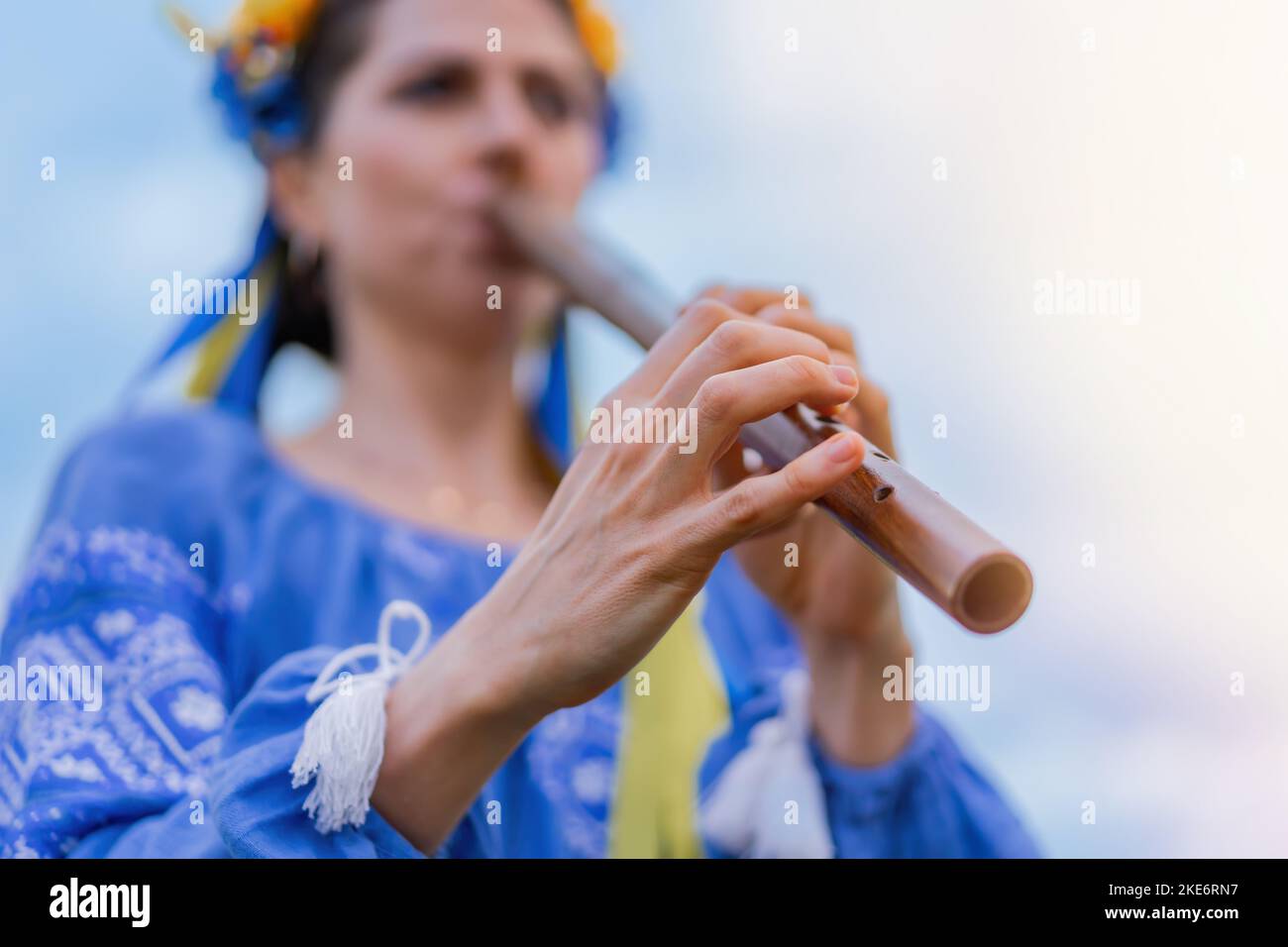 Woman playing woodwind wooden flute ukrainian sopilka outdoors. Folk music, culture concept