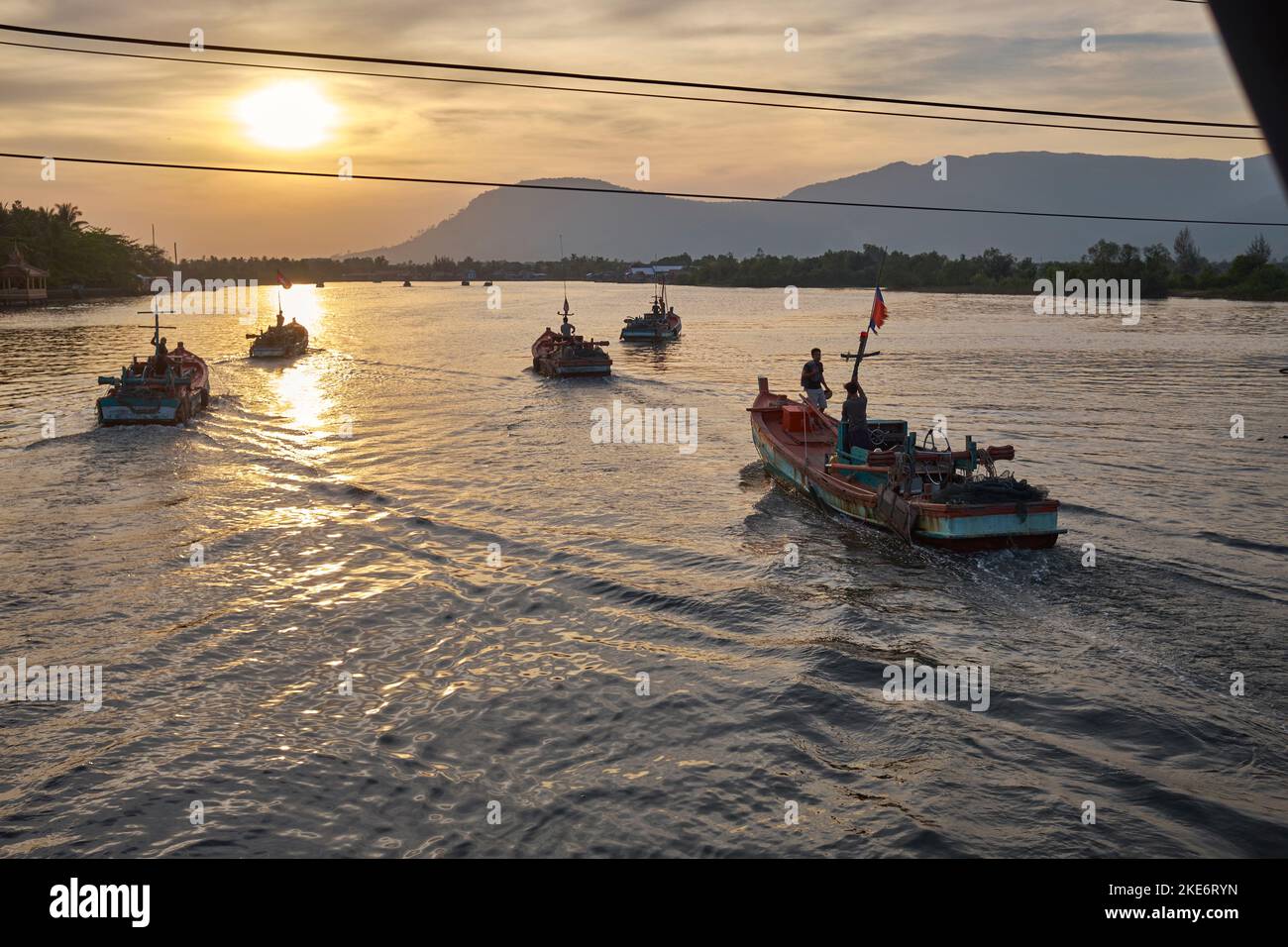 Fishing Boats heading out to sea at Dusk Kampot Cambodia Stock Photo