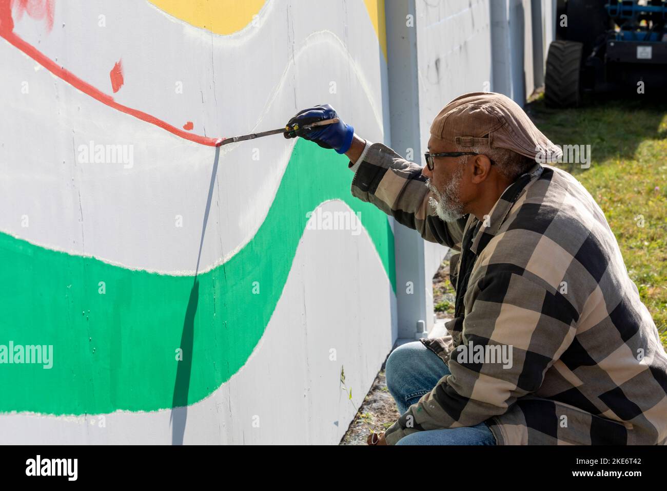 Detroit, Michigan - A block-long mural, designed by artist Hubert Massey, being painted on the sound barrier around the Stellantis Jeep plant. Part of Stock Photo