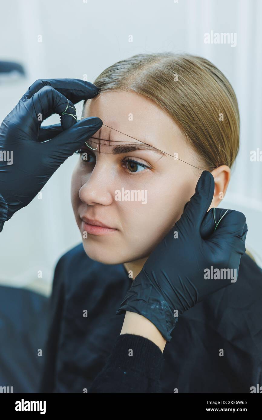 Young woman during professional eyebrow mapping procedure before