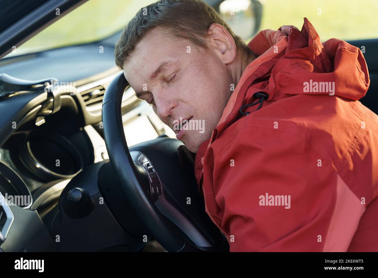 The tired driver sleeps in the car with his head bowed on the steering wheel. Security concept. Stock Photo