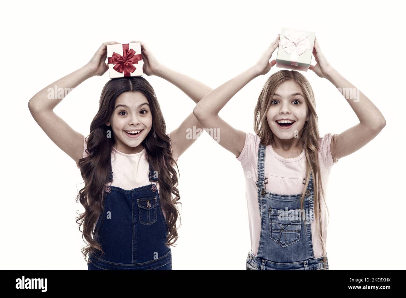 Learned how to gift wrap. Happy little girls holding gift boxes over head. Small children with gift packs on boxing day. Adorable kids with beautifull Stock Photo