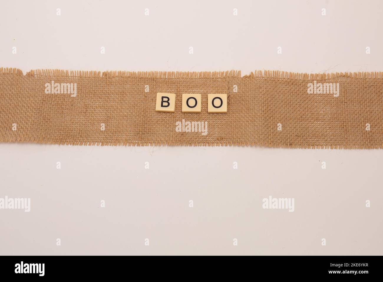 The letter tiles spelling word Boo laying on jute natural sackcloth ...