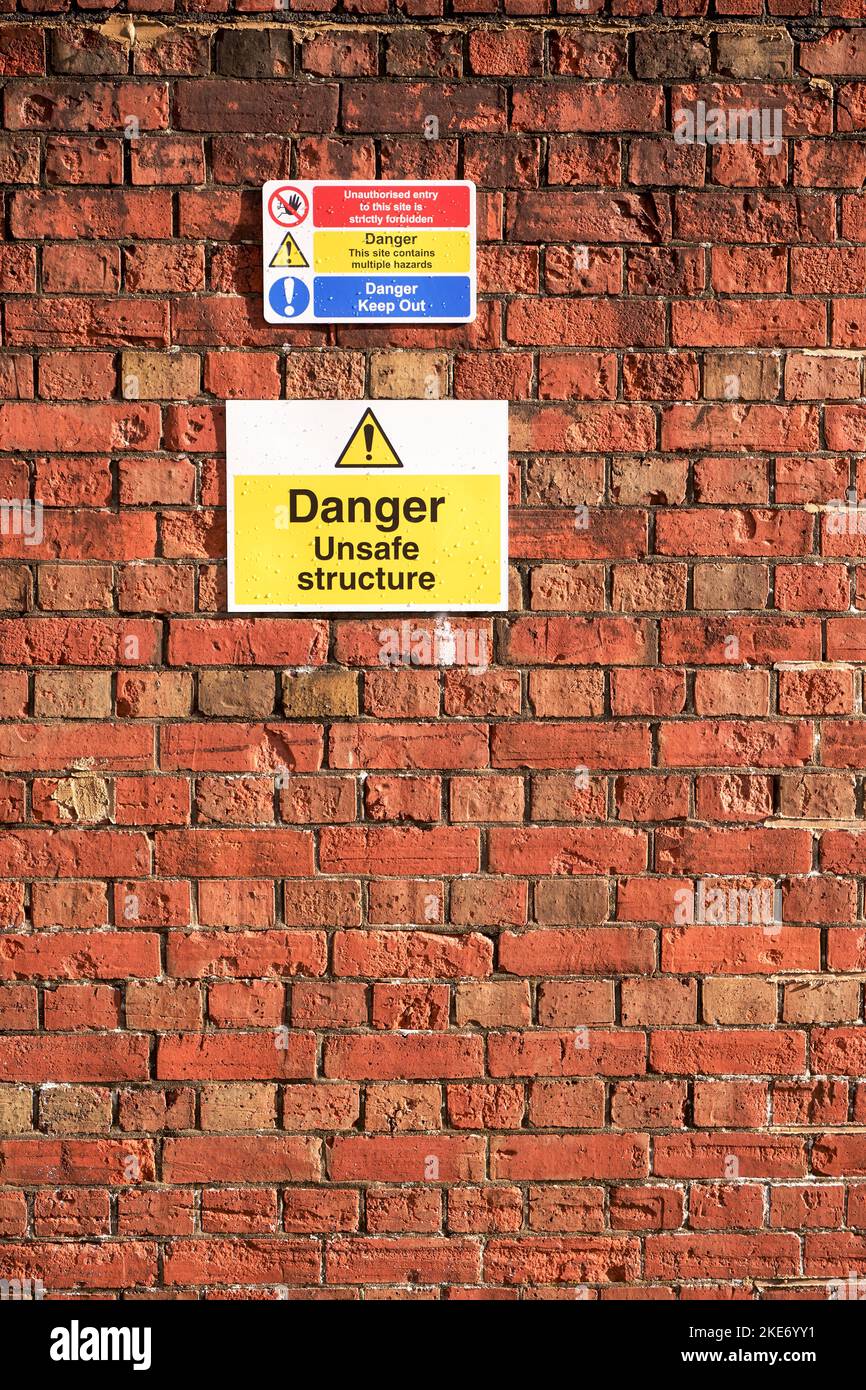 Danger unsafe structure warning sign attached to red brick wall Stock Photo