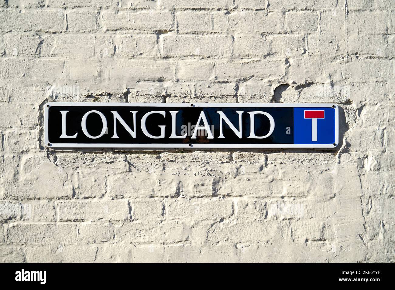 Longland street name sign on white painted brick wall Stock Photo