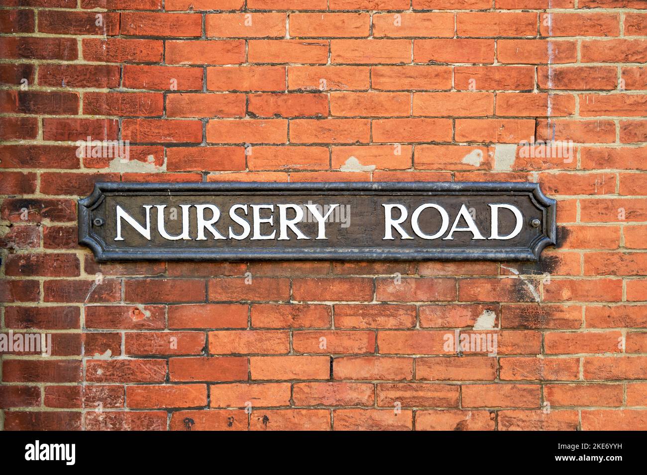Nursery road street name sign on red brick wall Stock Photo