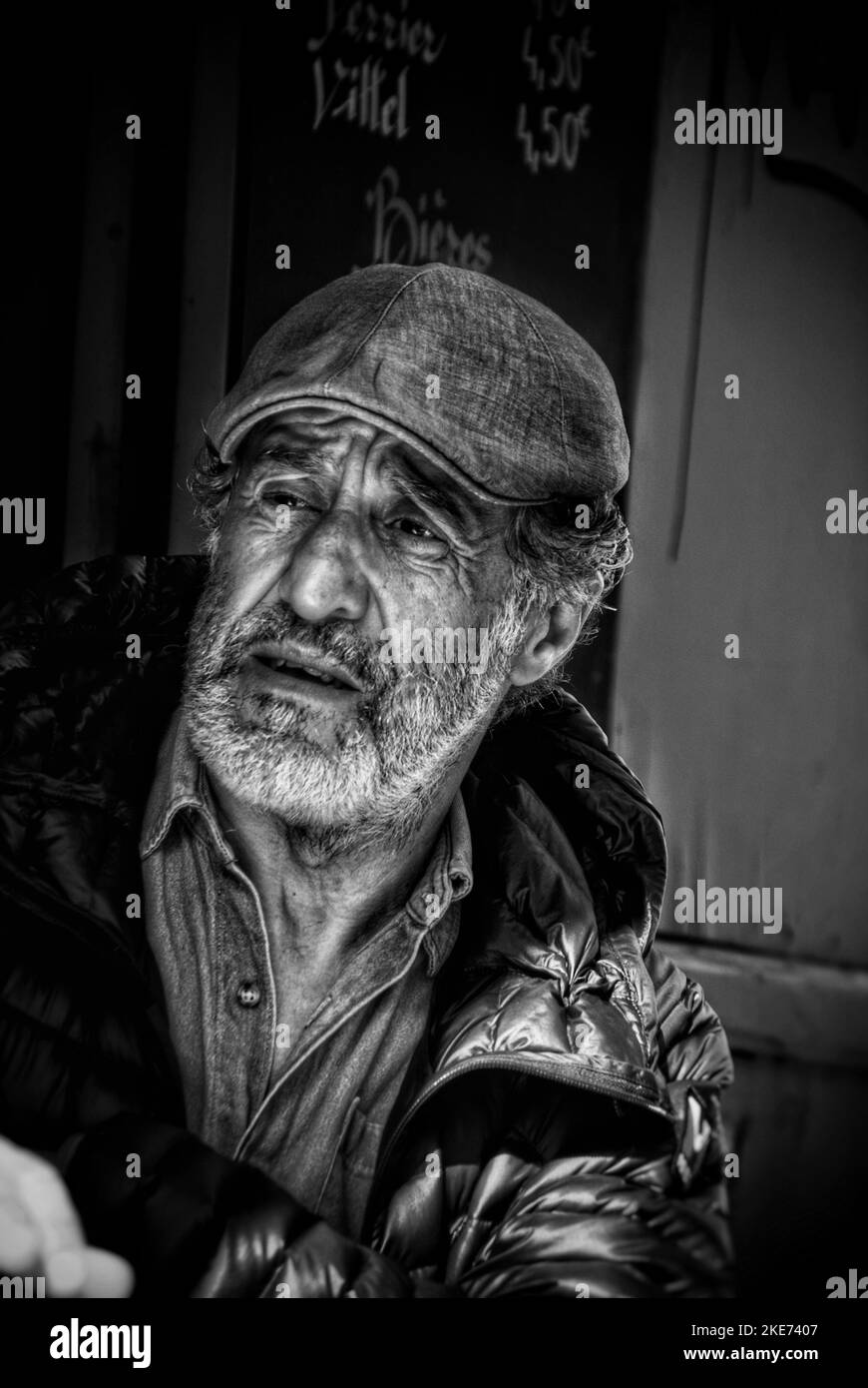 A vertical closeup grayscale of an old man with a hat and surprised face Stock Photo