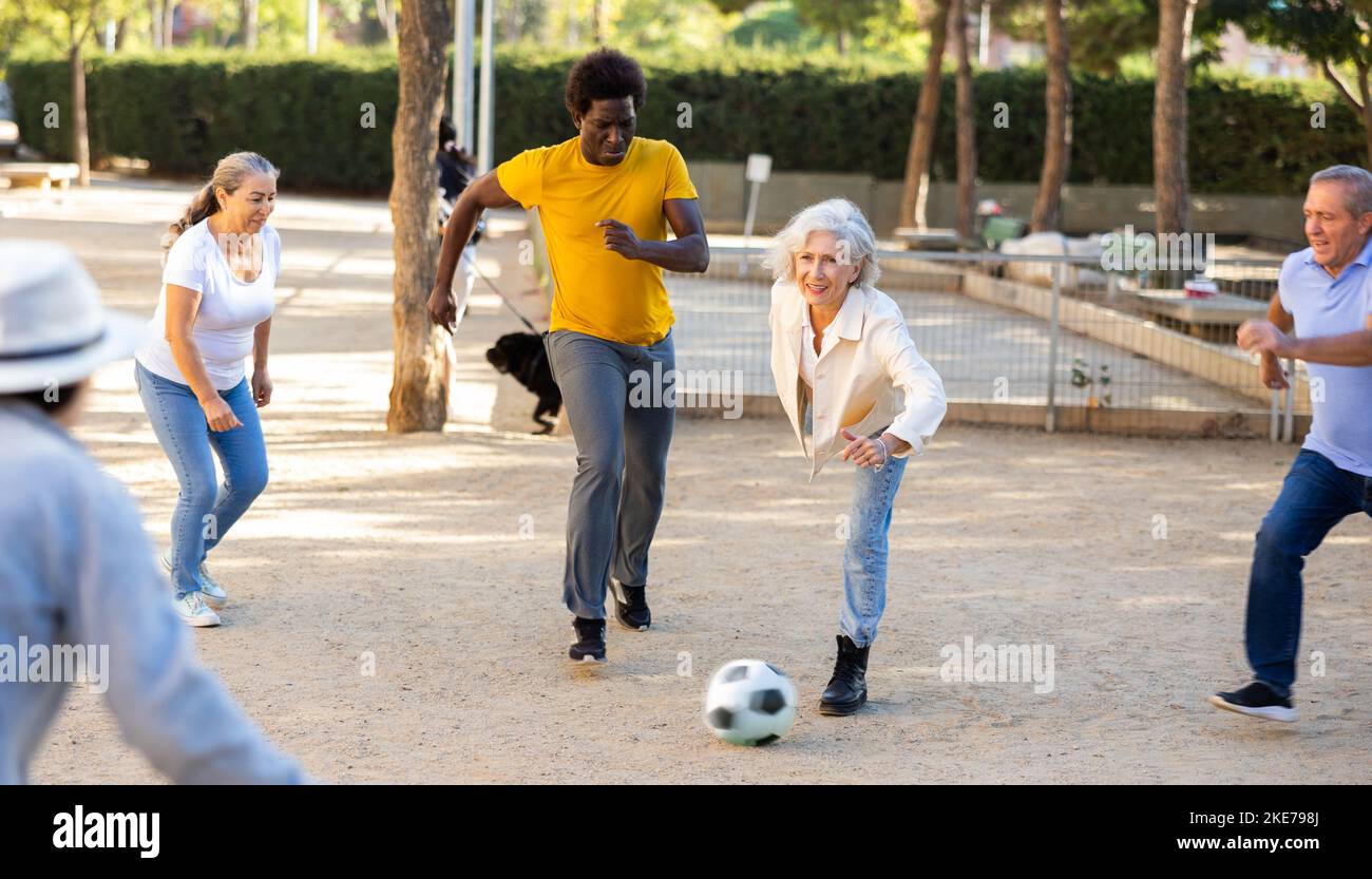 Happy mature people playing football in park Stock Photo