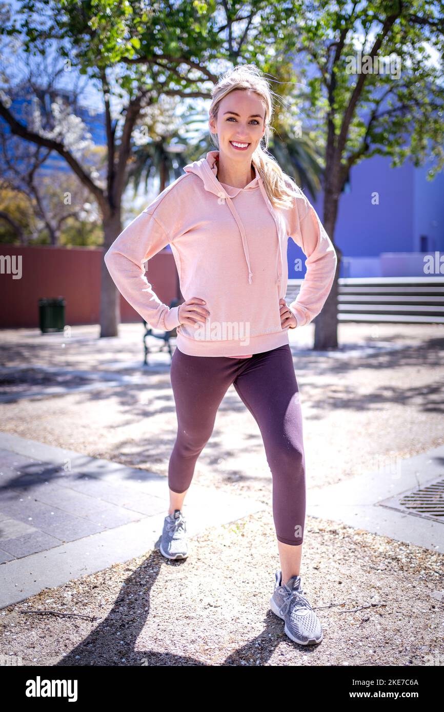 Young Woman Dressed in Pink, Grey, and Lavender Working Out in Downtown San Jose Park Stock Photo