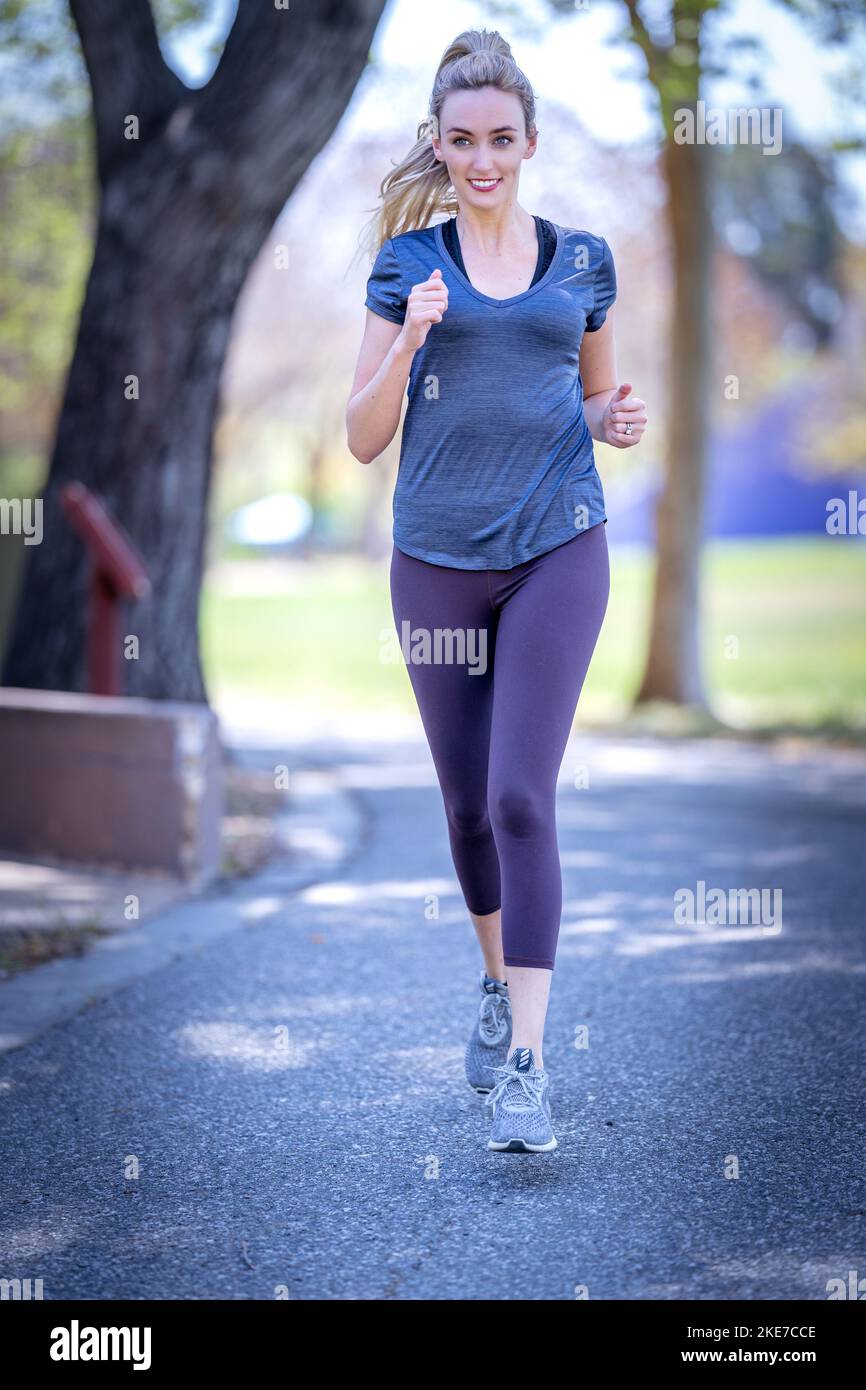 Young Woman Dressed in Pink, Grey, and Lavender Working Out in Downtown San Jose Park Stock Photo