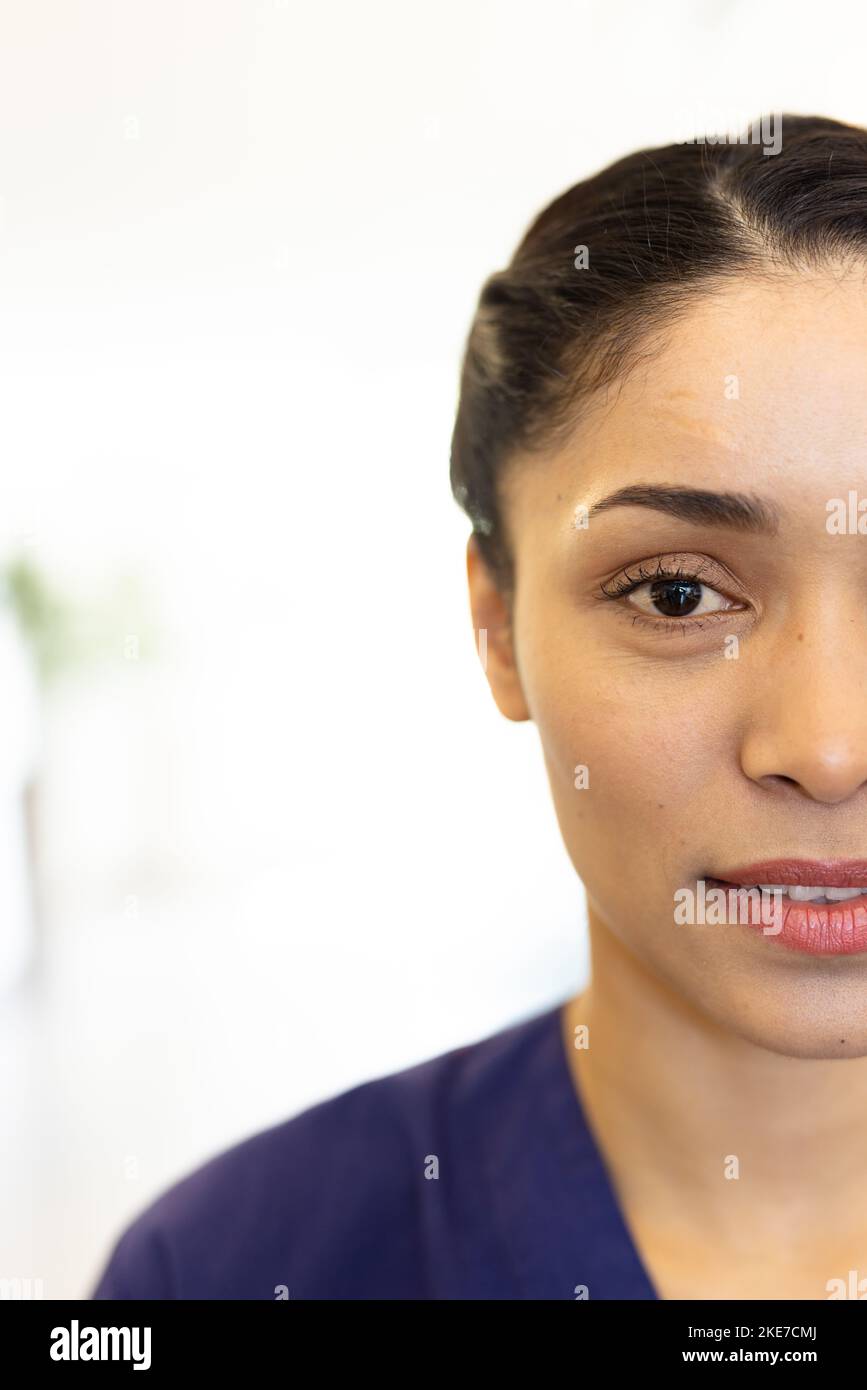 Vertical half face portrait of smiling biracial female healthcare worker, with copy space Stock Photo