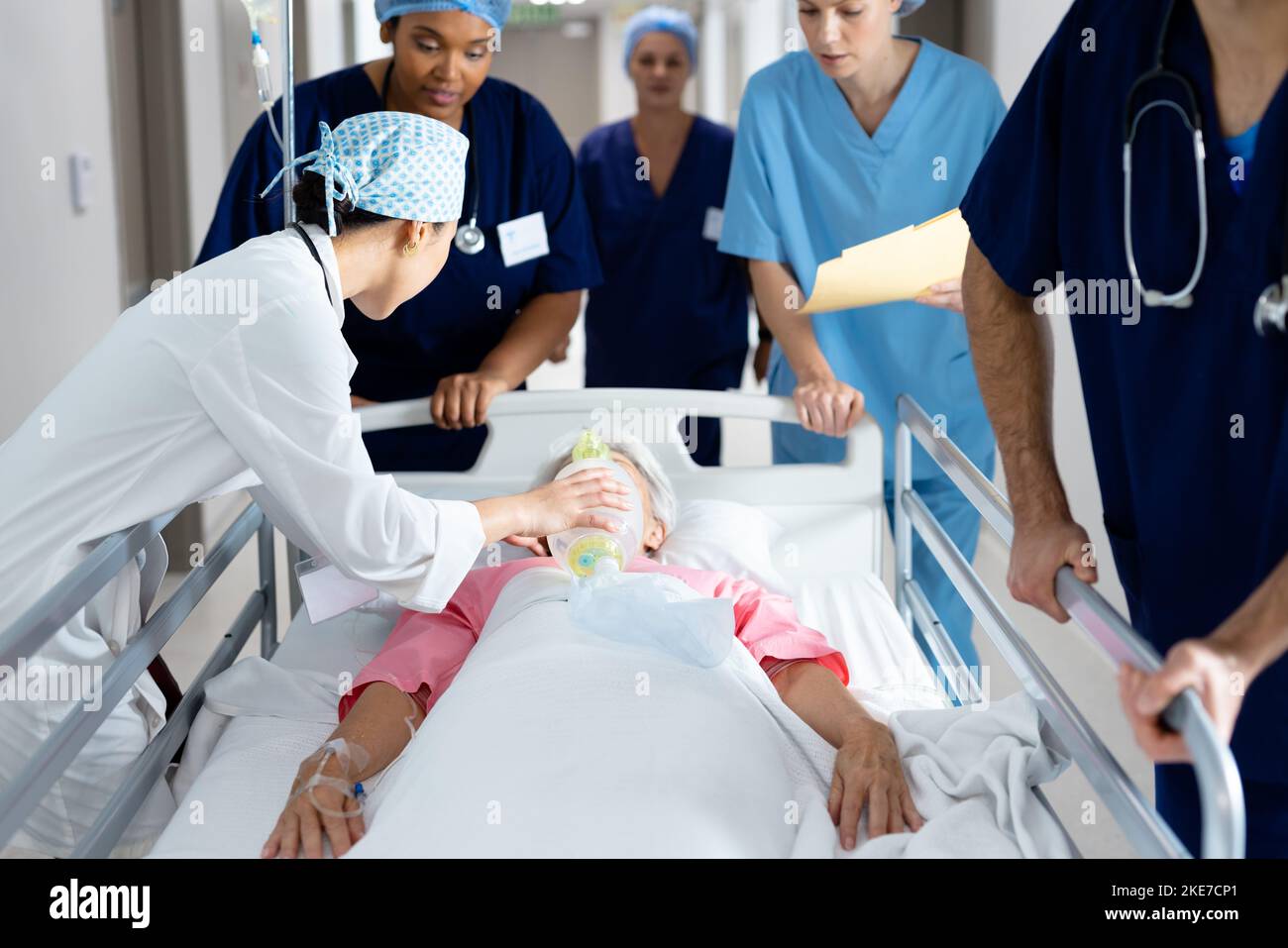Diverse group of healthcare workers giving ventilator to patient in bed in hospital corridor Stock Photo