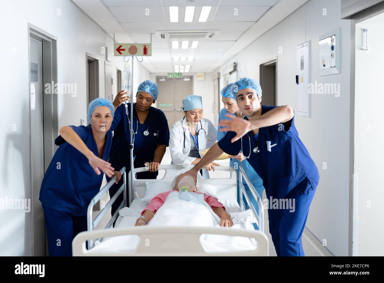 Diverse group of healthcare workers clearing the way for patient in bed in hospital corridor Stock Photo