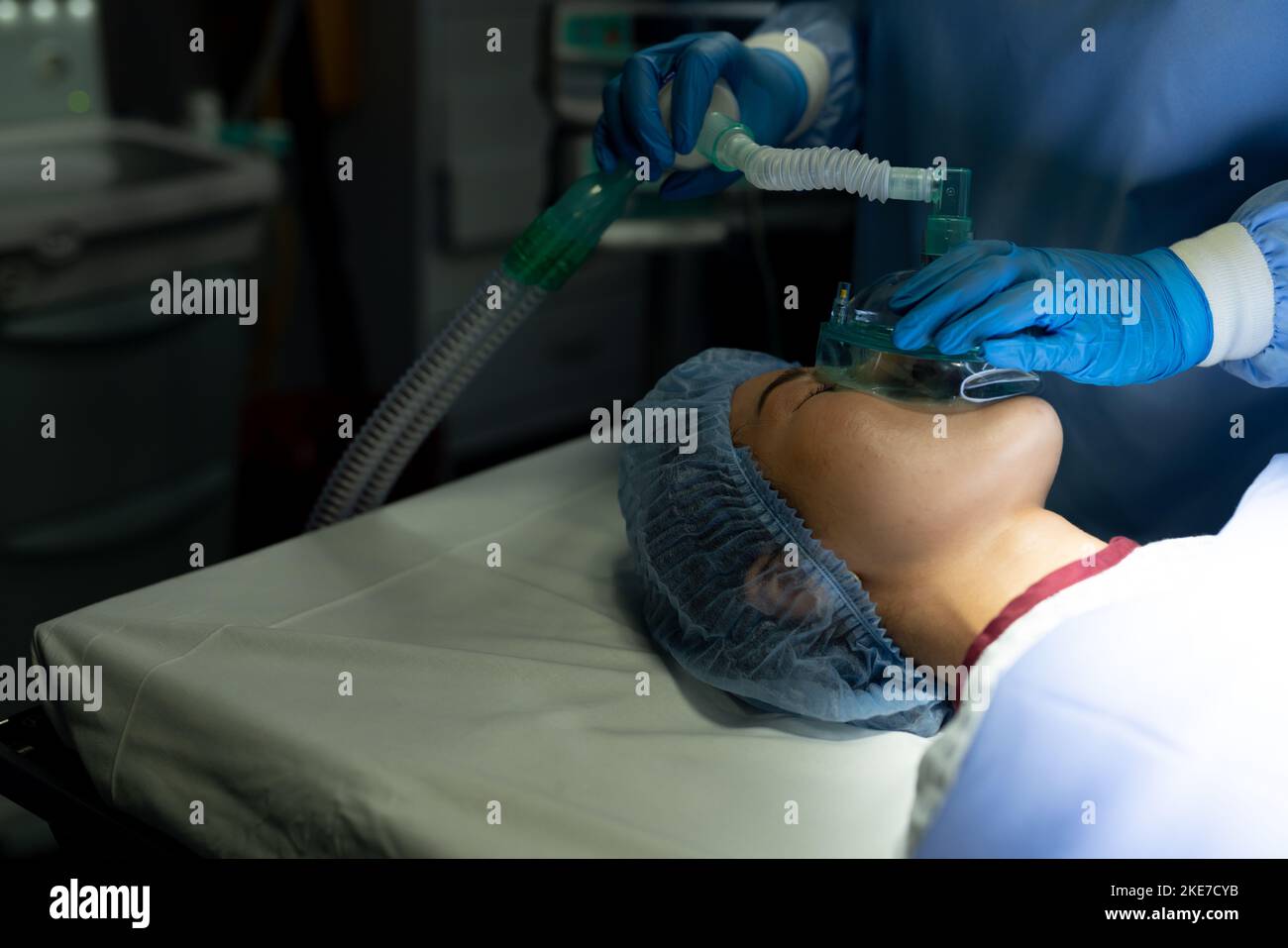 Hands of surgical tech giving gas to asian female patient on operating table in theatre Stock Photo
