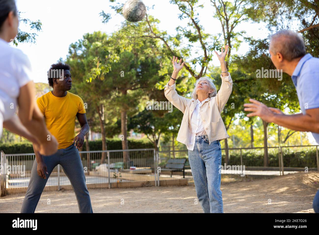 Positive multiracial friends of different ages throwing up a volleyball