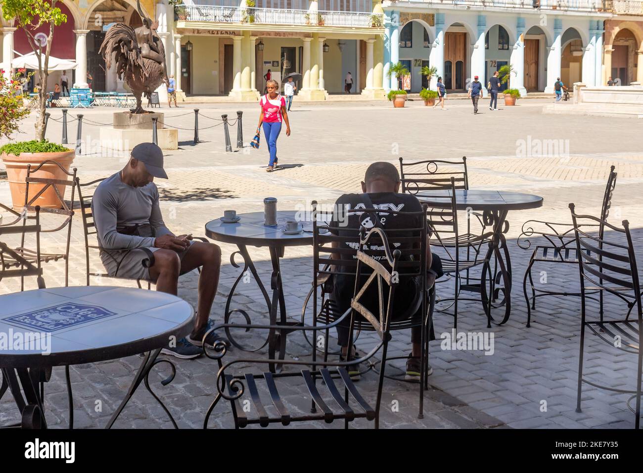Two Cuban men sit on an empty restaurant patio in Plaza Vieja. Contrary to the usual, the area is empty of tourists. Stock Photo