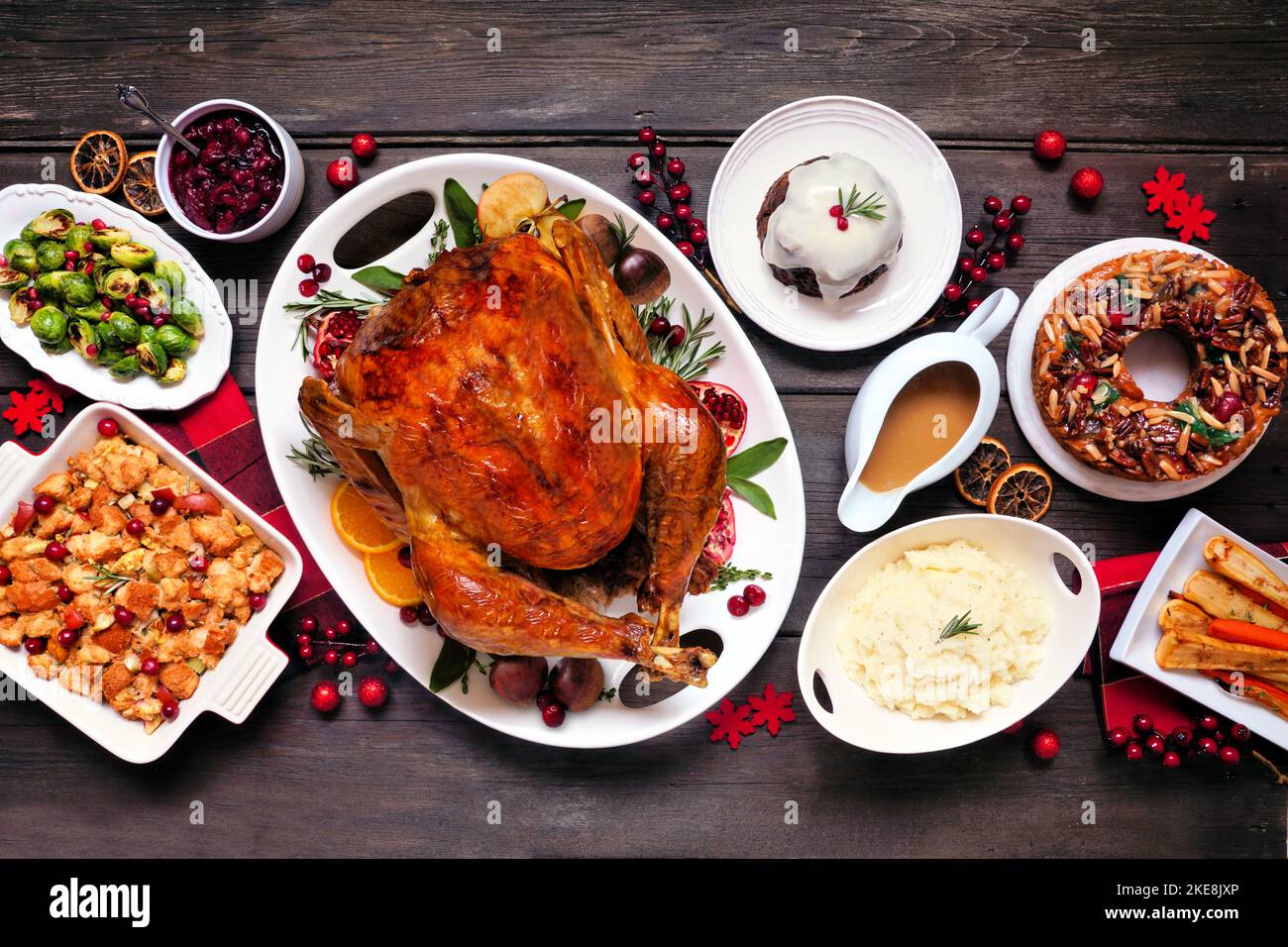 Traditional Christmas turkey dinner. Top view table scene on a dark wood background. Turkey, potatoes and sides, dressing, fruit cake and plum pudding Stock Photo