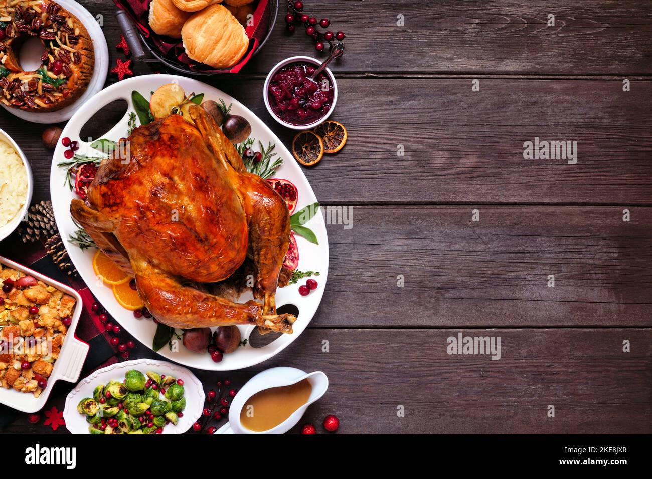 Traditional Christmas turkey dinner. Top down view side border on a dark wood banner background. Turkey with sides, dressing and fruit cake. Stock Photo