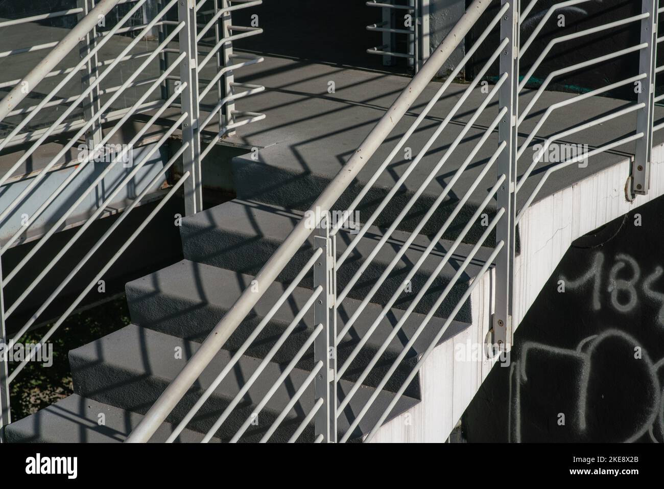 staircase architecture: detail of the external stairs with concrete steps and the railing and handrail and in white painted steel. Stock Photo