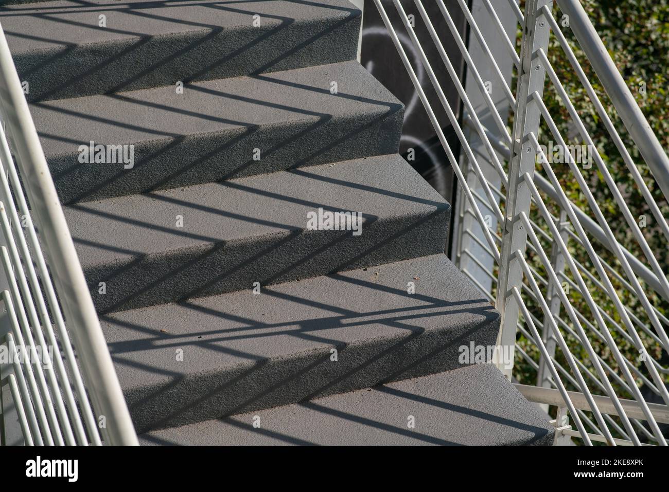 staircase architecture: detail of the external stairs with concrete steps and the railing and handrail and in white painted steel. Stock Photo