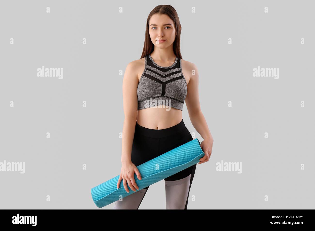 Sporty young woman with yoga mat on light background Stock Photo - Alamy