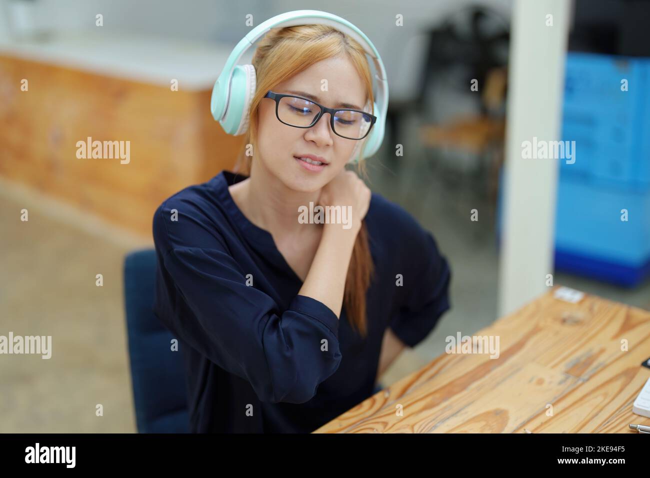 Portrait of an Asian teenage girl feeling pain in the neck muscles after working on a laptop computer for a long time. Office Syndrome concept Stock Photo