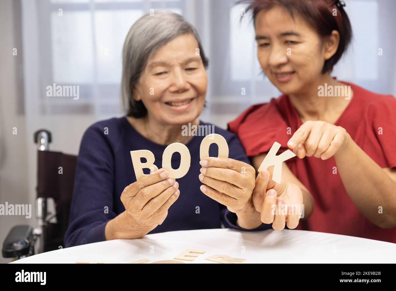 Elderly woman playing alphabet games for improve mental health and memory with daughter Stock Photo