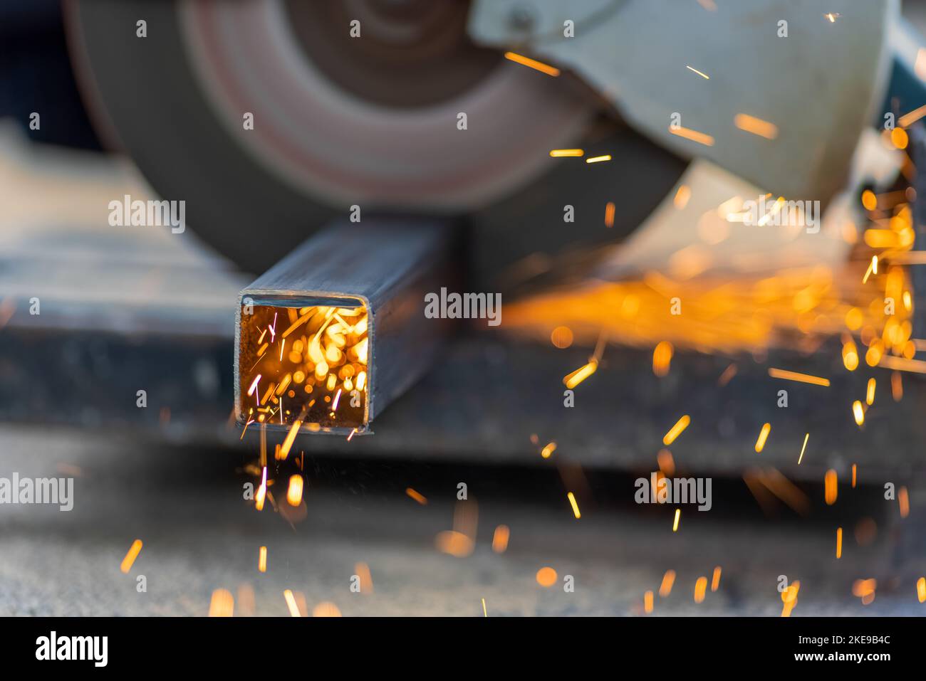 Worker cutting steel rectangular pipe in construction site. Stock Photo