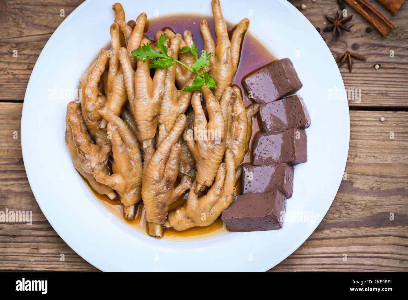 Cooking chicken feet foot stew on white with herbs and spices