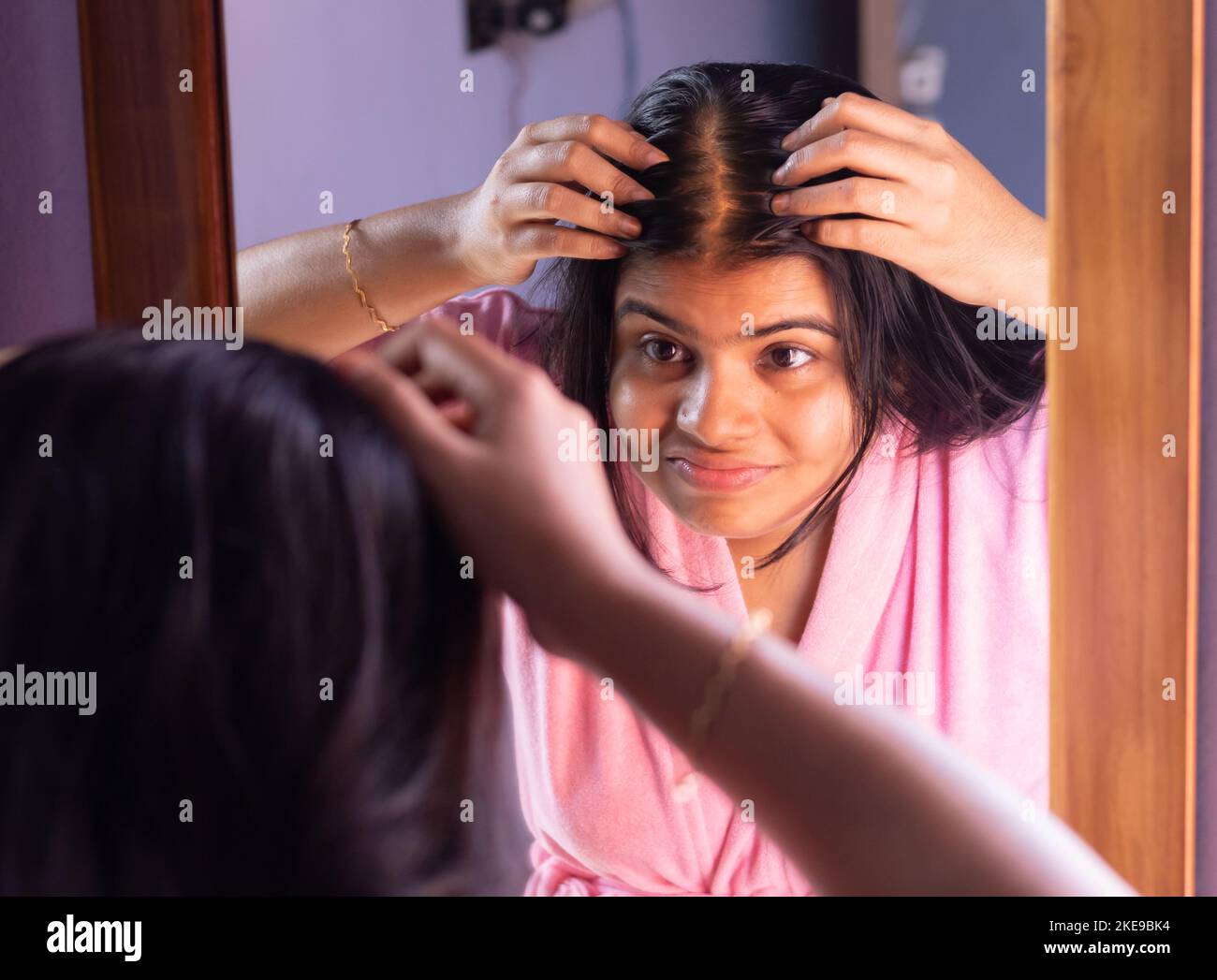 An Indian woman checks hair loss problem in front of mirror Stock Photo