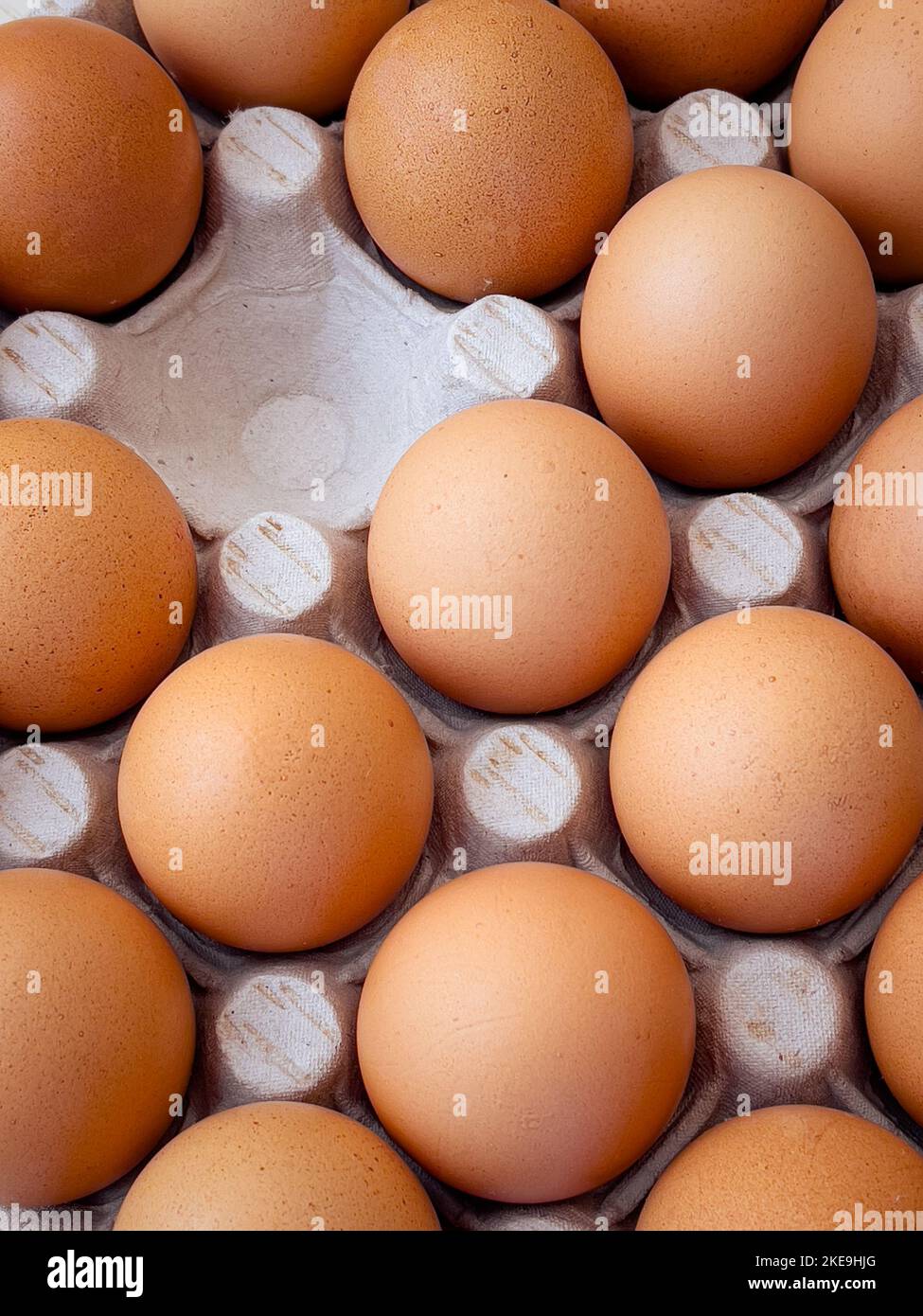 Brown eggs in cardboard egg box. Top view of raw organic chicken eggs in carton. Stock Photo