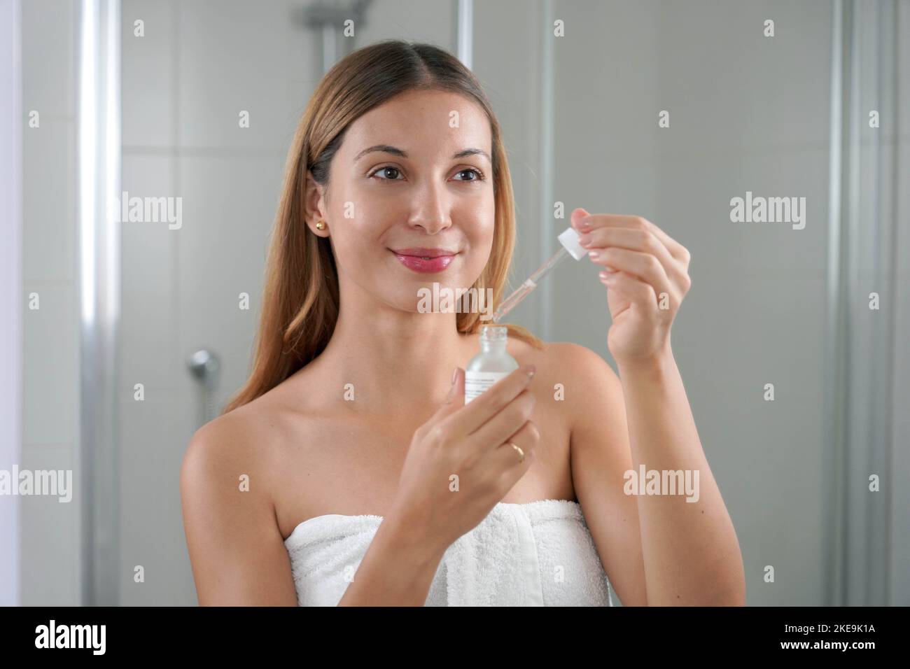 Portrait of a young woman applying Retinol on her face at home. Skin care routine. Stock Photo