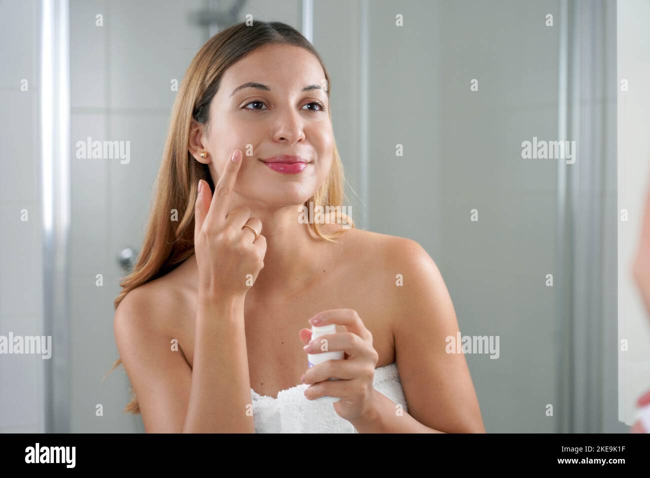 Skin care woman applying cream with retinol anti-signs in the bathroom Stock Photo