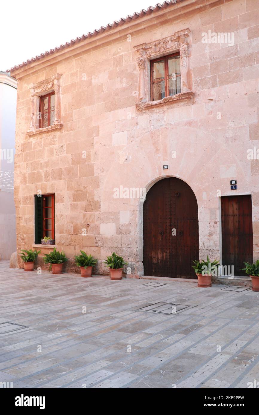 Ancient stone wall with wood door and pot flowers by a street in