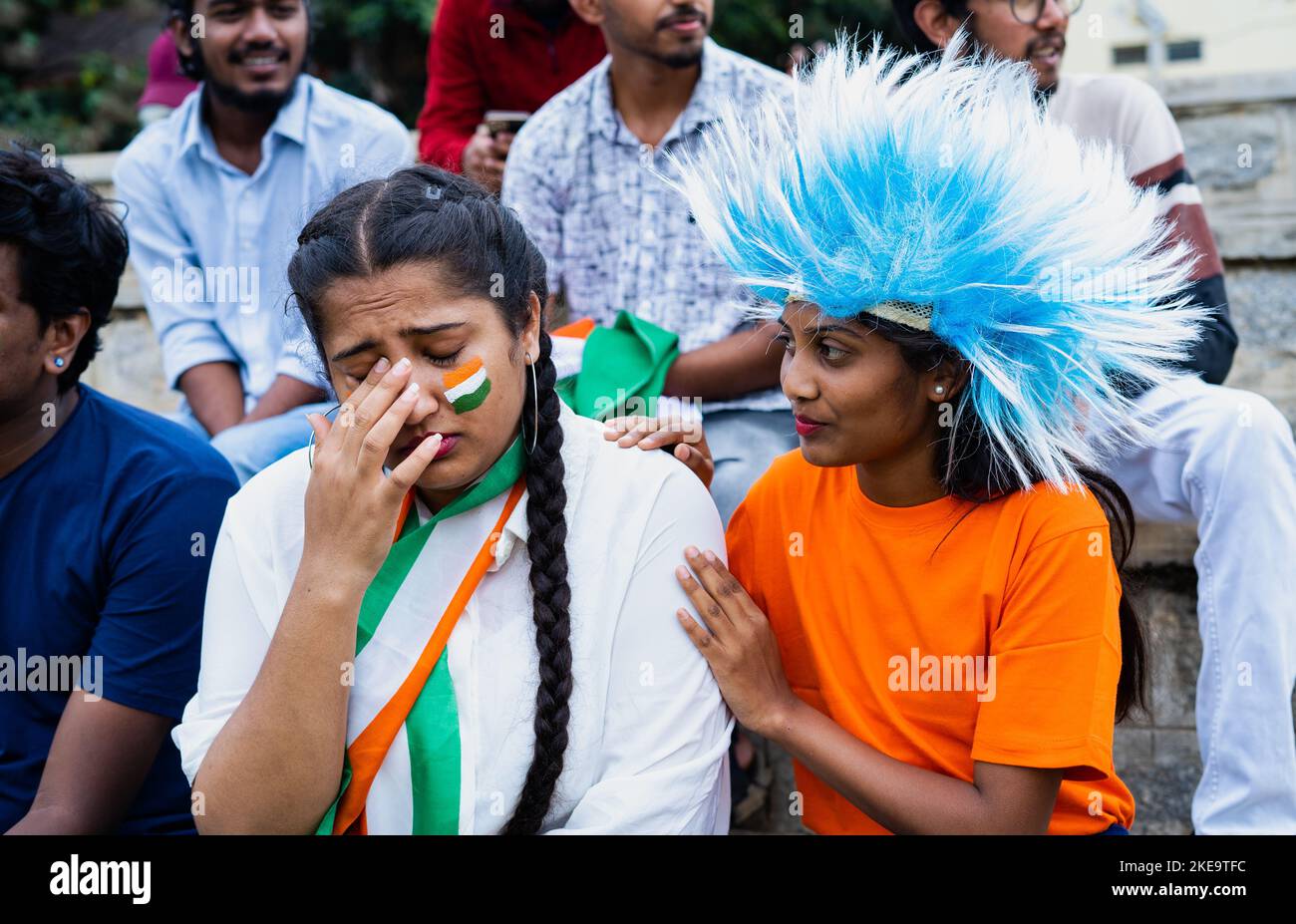Friend consoling sad Indian girl fan due to lost in cricket world cup game at stadium - concept of failure, support and emotional Stock Photo