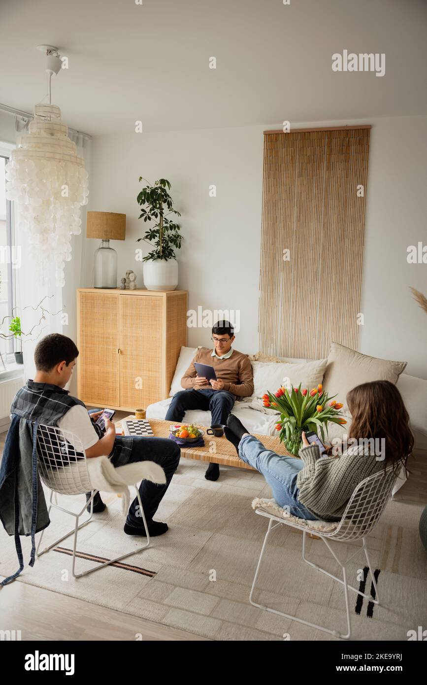 Siblings using phones and tablet at home Stock Photo